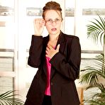 Pic of Bespectacled secretary Helena in black nylon stockings flashes her bush when doing striptease