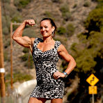 Pic of Bodybuilder Kirsten Klipp Van Arsdale flexes her muscles in a dress on a road