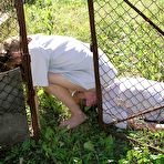 Pic of Caucasian girl straddles a man's face outside of a doghouse in a yard