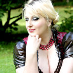 Pic of Overweight blonde Darkwing Zero models on a lawn in a rubber dress